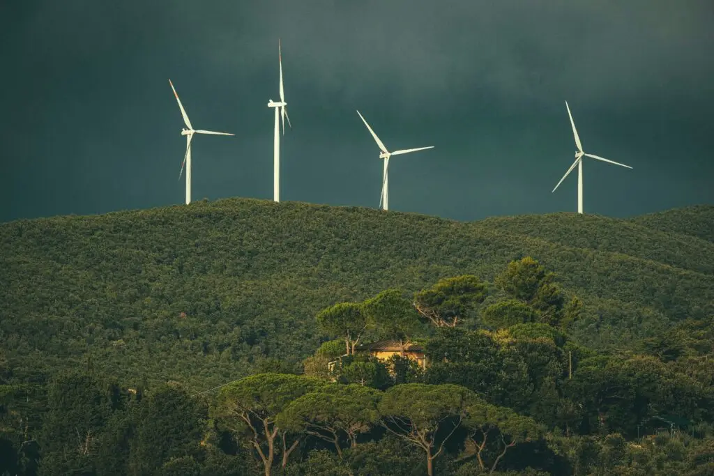 Wind turbines stand above lush green hills, showcasing renewable energy in nature.
