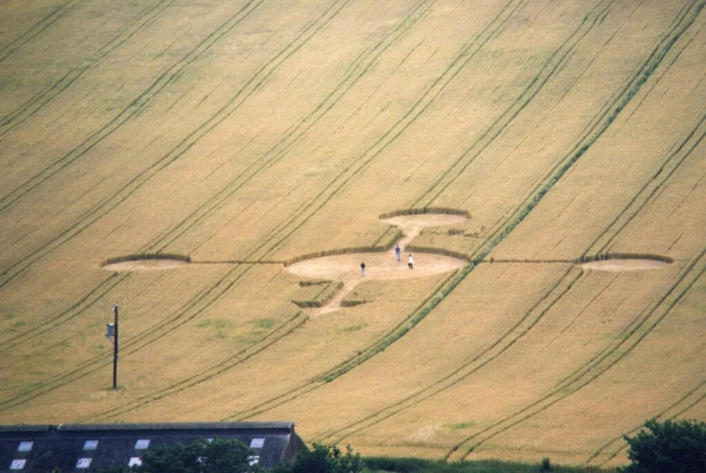 Intriguing aerial shot of a crop circle in a vast farm field with people exploring.